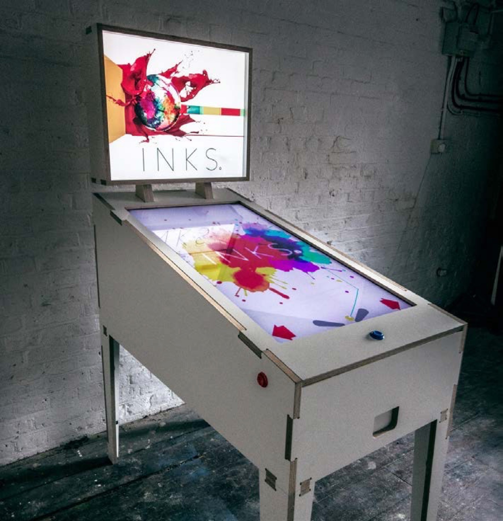 The physical INKS exhibition table with its painted playfield and upright display.